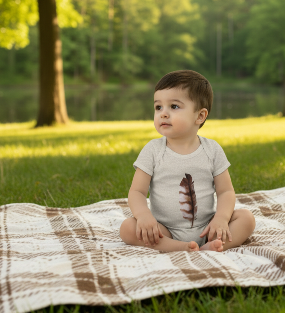 Child sitting on a blanket in a park with trees and grass in the background