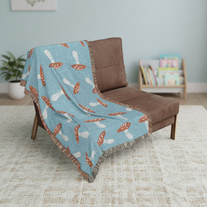 Blue blanket with mushroom pattern draped over a brown chair on a white background
